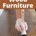 A gloved hand staining wood with a paintbrush, text reads How to Stain Wood Furniture.