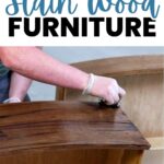 Person staining wooden furniture with a rag