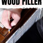 A hand uses a small brush to stain wood filler on a wooden surface. Text reads “Staining Wood Filler.”.