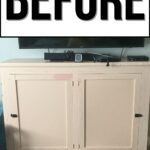 A beige, worn cabinet with cracked paint sits below a TV