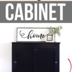 Black cabinet with newly added short legs, home sign on top, and red arrow pointing to a cabinet leg.