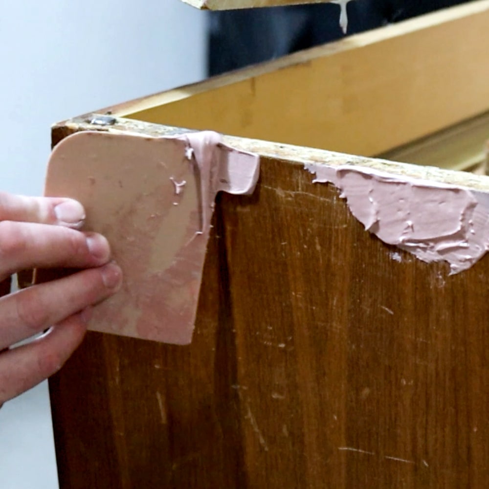 applying bondo on damaged part of the furniture