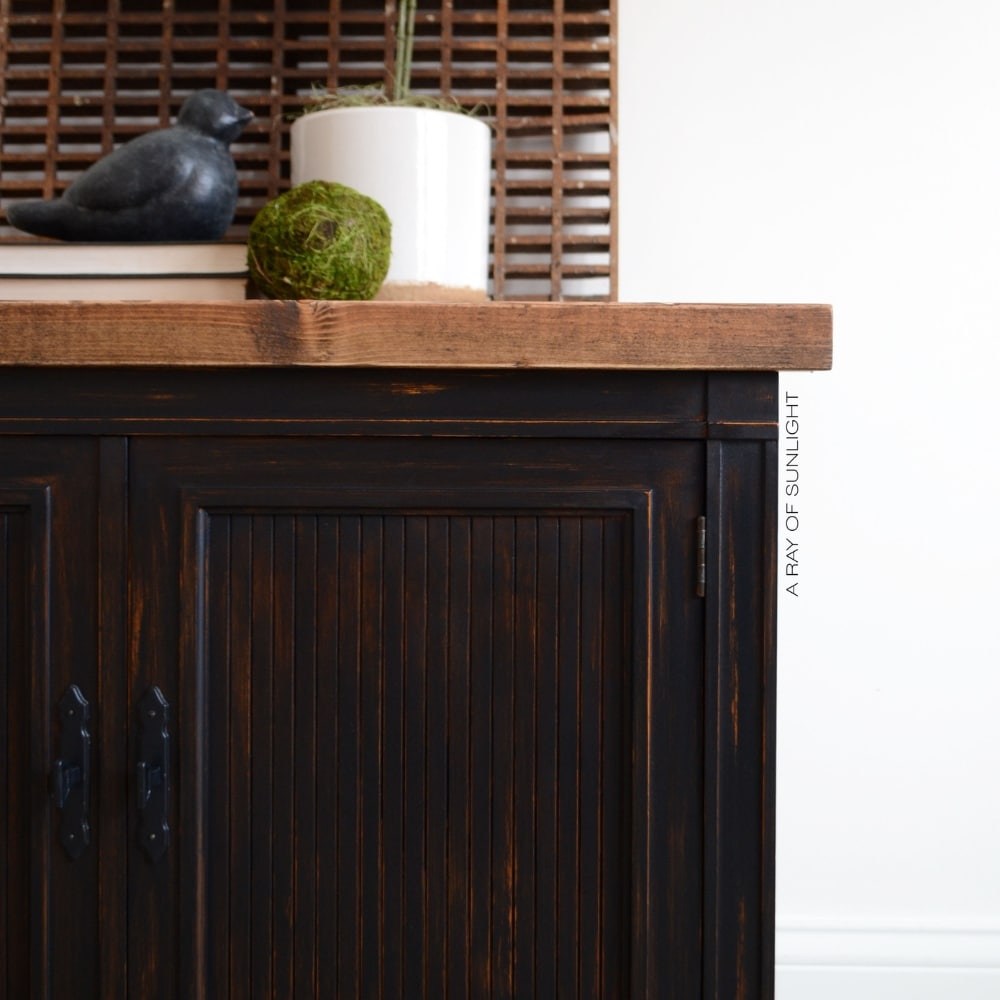 closeup of the black painted cabinet with stained wood rustic top