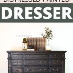 A dark distressed dresser with brass handles, decorated with plants, books, and vintage items on top.