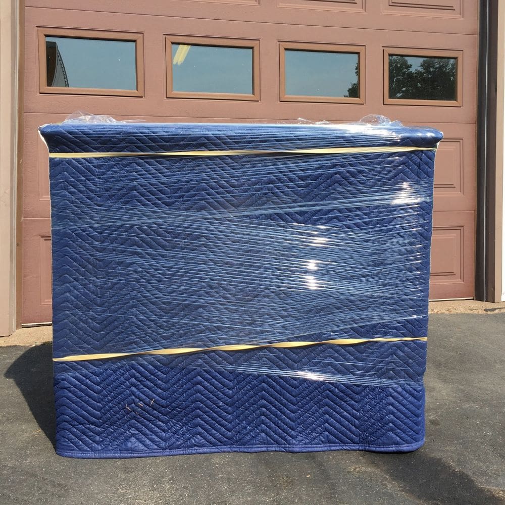 photo of a large furniture wrapped in shipping blankets with plastic wrap