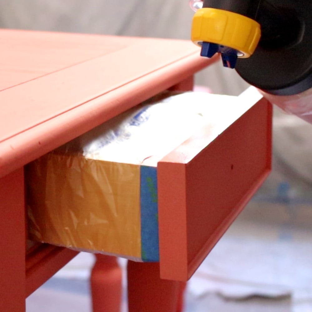 Spraying the edges of the drawer on an end table with paint