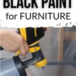 Hand using a paint sprayer to apply black paint to a surface