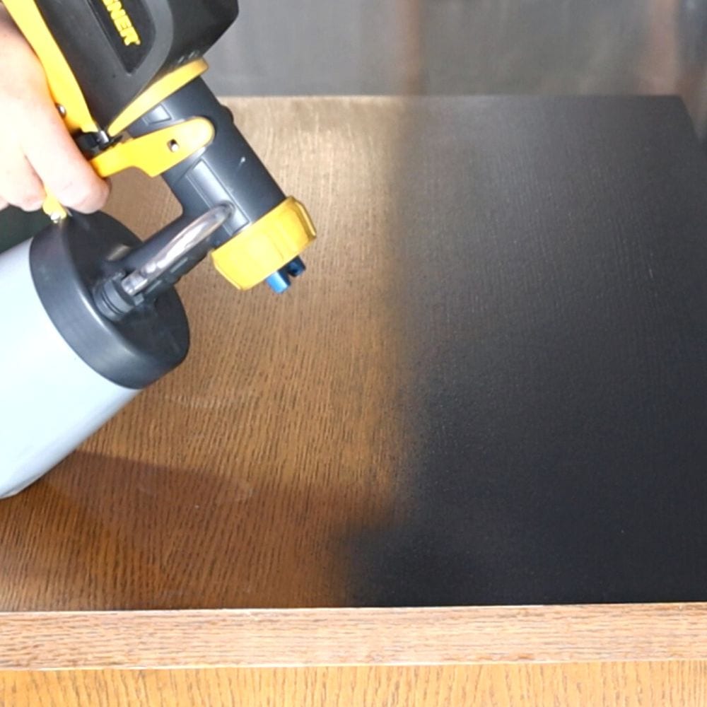 spraying Heirloom Traditions Paint in Iron Gate onto furniture using a paint sprayer