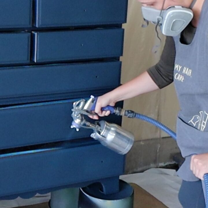 Natalie donning a respirator while spraying a dresser