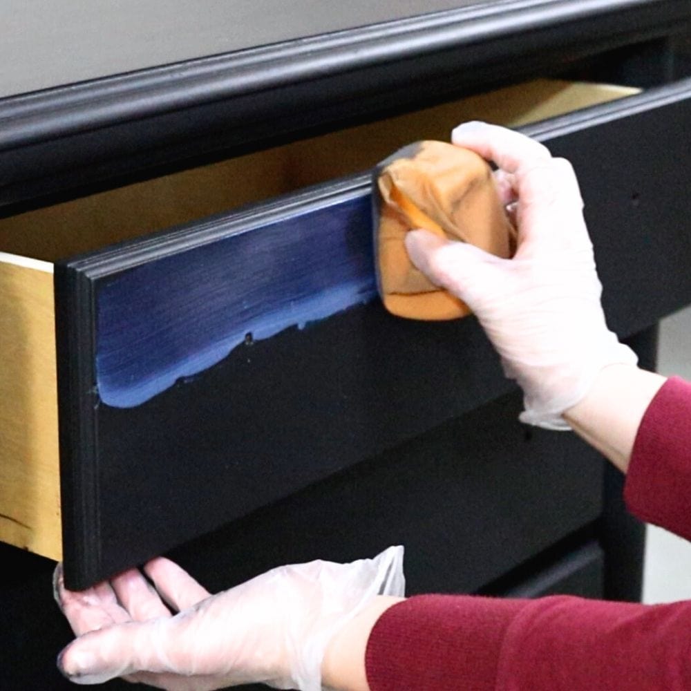 applying water-based polyacrylic by hand on a furniture drawer with a sponge