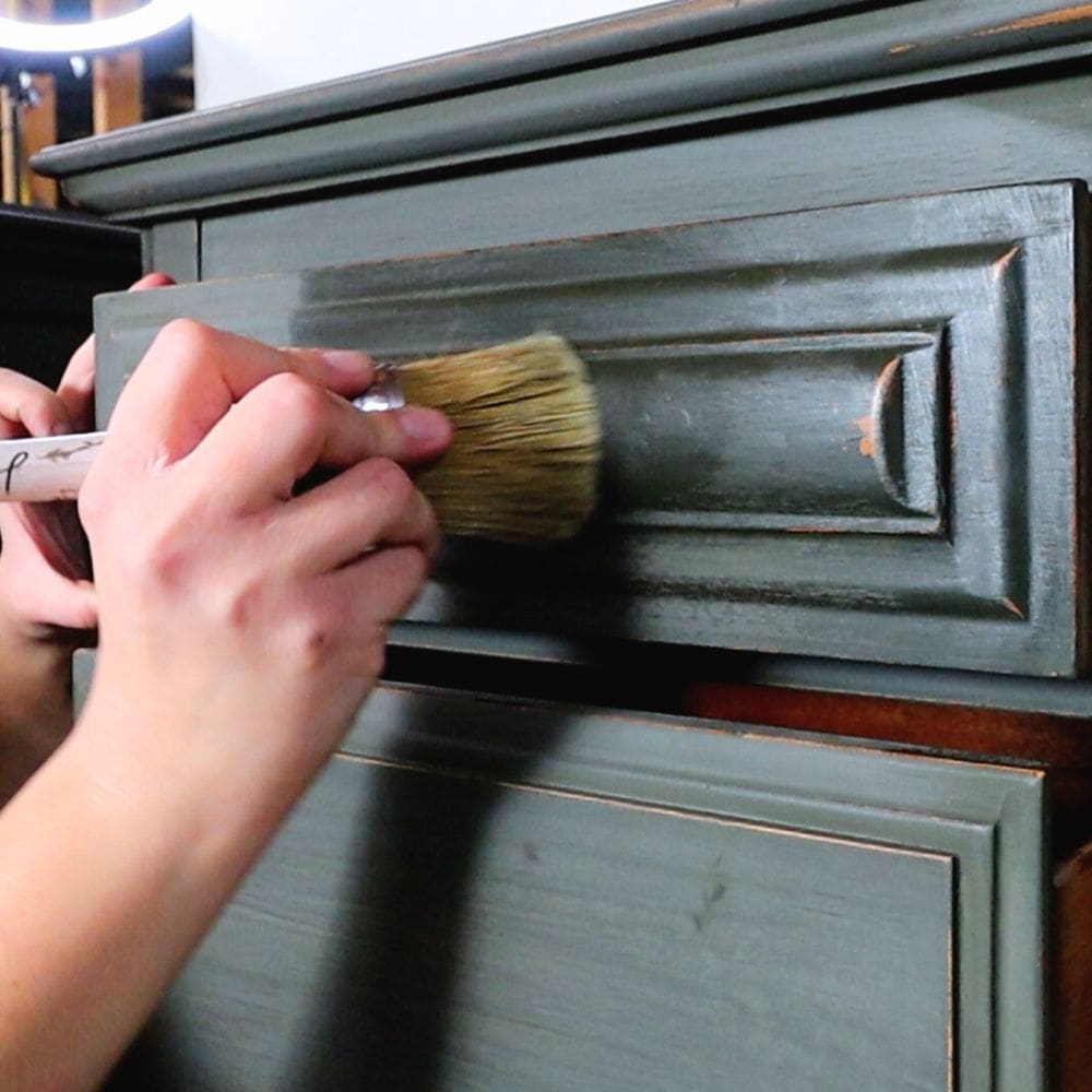 applying wax on a furniture drawer with a brush