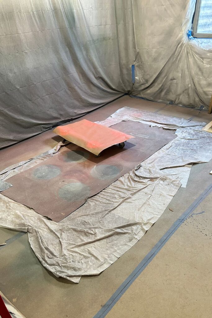 an indoor spray booth with plastic and cardboard protection around the wall and on the floor