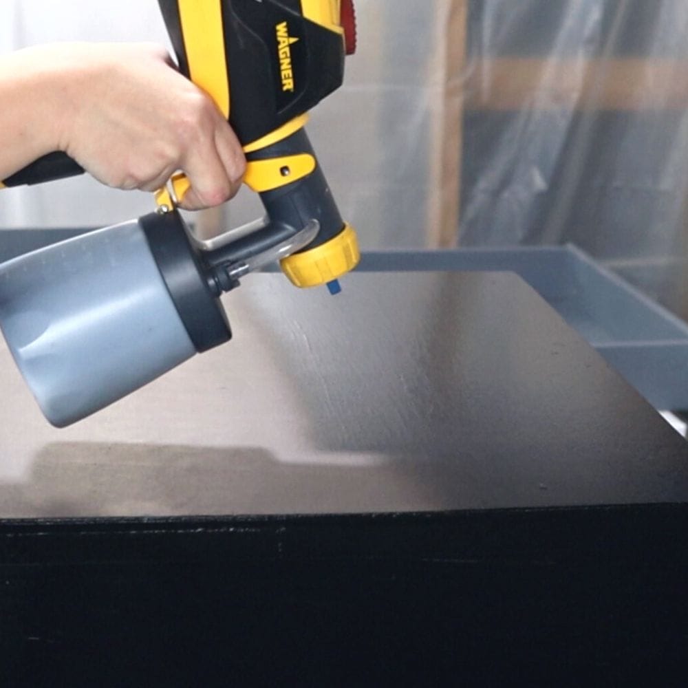 spraying fusion mineral paint in coal black onto furniture using paint sprayer