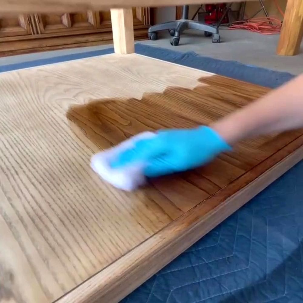 using a staining pad to stain the wood furniture