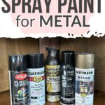 Five cans of different spray paints for metal are lined up on a wooden surface under a sign reading Best Spray Paint.