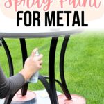 Person spray painting black metal table legs outdoors, table propped on red and white cans on the grass.