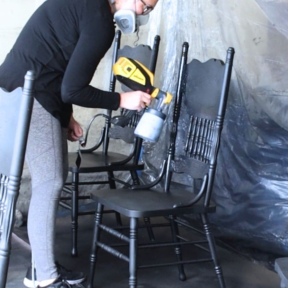 spraying black paint onto a chair