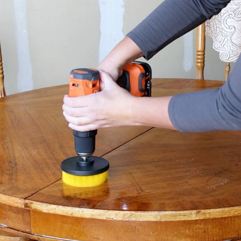 using a drill brush to clean surface of old table before painting