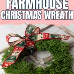 A DIY Christmas wreath made of greenery with a red and green bow on a rustic wooden surface.