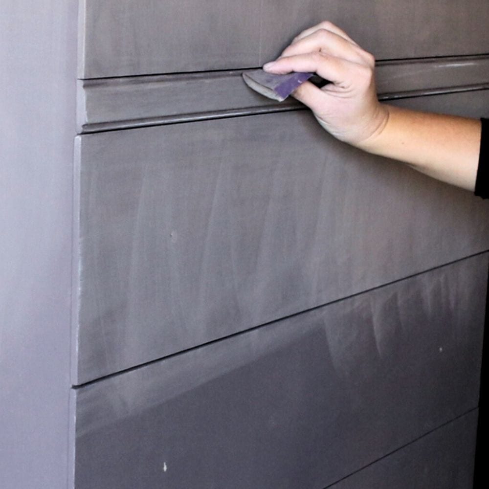 Using folded sandpaper to sand crevices of furniture
