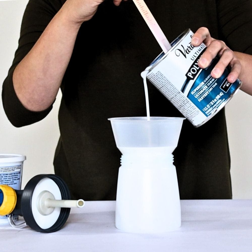 Pouring polyurethane into a sprayer container with paint filter