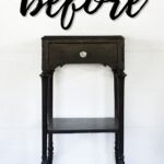 A small black vintage side table with before written above it in large script.
