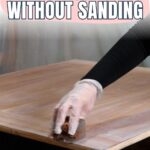 Gloved hand applying wood stain to a tabletop, text reads How to Change Wood Color Without Sanding.