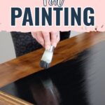 A hand uses a paintbrush to apply primer to a wooden surface; text reads Priming Wood for Painting.