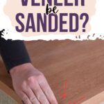 A hand sanding the edge of a wooden surface with text: Can veneer be sanded?.