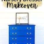 Bright blue nursery dresser with gold handles, a framed quote, and white flowers on top against a white wall.