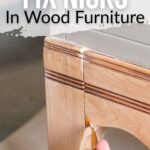 A hand uses a brush to fix a nick in light wood furniture; text reads How to Fix Nicks in Wood Furniture.