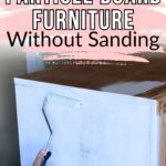 A hand uses a paint roller to apply white paint on a particle board dresser; text: How to Paint Particle Board Furniture Without Sanding.