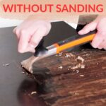 Hands scraping paint off wood with a tool, text says How to remove paint from wood without sanding.