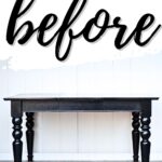 A black wooden table with turned legs against a white wall, with before written above in large script.