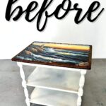 Small white table with ocean scene on top and the word before written above in large script.
