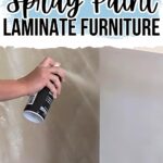 Hand spraying white paint on laminate furniture