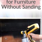A hand sprays black paint on a wooden dresser with text: Best black paint for furniture without sanding.
