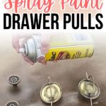 Hand spray painting brass drawer pulls on a brown surface with text: How to Spray Paint Drawer Pulls.