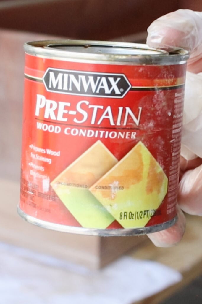 Hand holding a can of Minwax Pre Stain Wood Conditioner