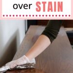 Gloved hand applying stain to a wooden surface