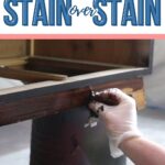 A gloved hand stains wood on a piece of furniture