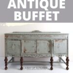 A distressed green painted antique buffet with ornate details and dark legs against a white background
