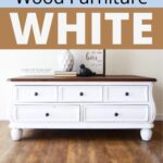 White-painted wood dresser with dark top, on wooden floor, with decorative items and wall art on top.