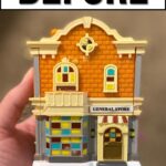 A hand holds a miniature model of a general store with BEFORE written above it.