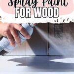 Hand spraying white paint onto a wooden surface with the text Best White Spray Paint for Wood above.