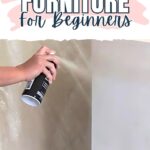 A hand spray painting a piece of furniture white, with text: How to Spray Paint Furniture for Beginners.