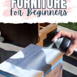 A hand spray paints a small wooden cabinet white outdoors; text reads “How to Spray Paint Furniture for Beginners.”.