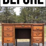 A wooden desk with six drawers outdoors, under a large BEFORE sign. Trees are in the background.