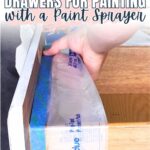 Hand applying painters tape and plastic to a drawer to prepare for painting with a sprayer.