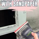 Hand using an electric sander on a painted wooden drawer with text: How to Distress Furniture with Sandpaper.